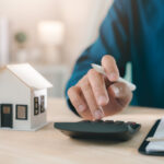 Mortgage loan interest rate payment signing real estate model planning property investment handled by expert using calculator with house keys and documents for home finance purchase deal