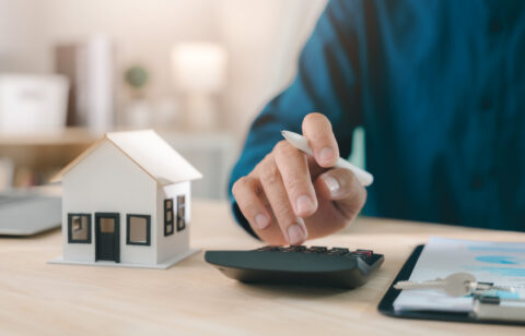 Mortgage loan interest rate payment signing real estate model planning property investment handled by expert using calculator with house keys and documents for home finance purchase deal