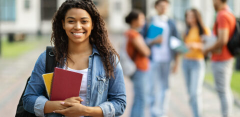 Loans for education concept. Portrait of happy black female student posing outdoors