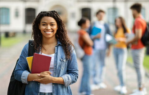 Loans for education concept. Portrait of happy black female student posing outdoors
