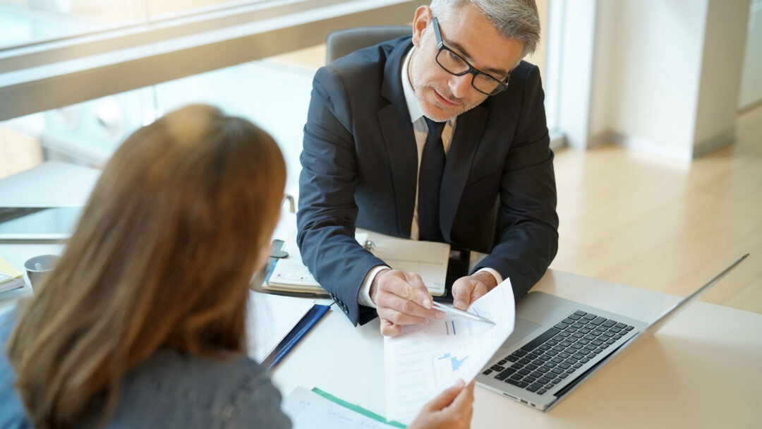 Woman in banker's office signing financial loan for project