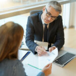 Woman in banker's office signing financial loan for project