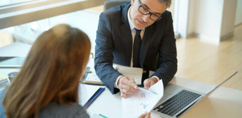 Woman in banker's office signing financial loan for project