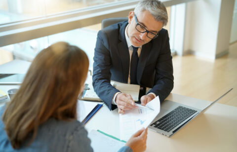 Woman in banker's office signing financial loan for project
