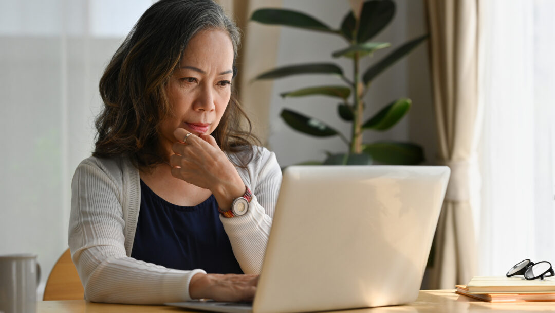 Old woman work at home using notebook computer.