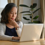 Old woman work at home using notebook computer.