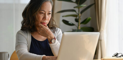 Old woman work at home using notebook computer.