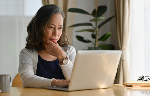 Old woman work at home using notebook computer.
