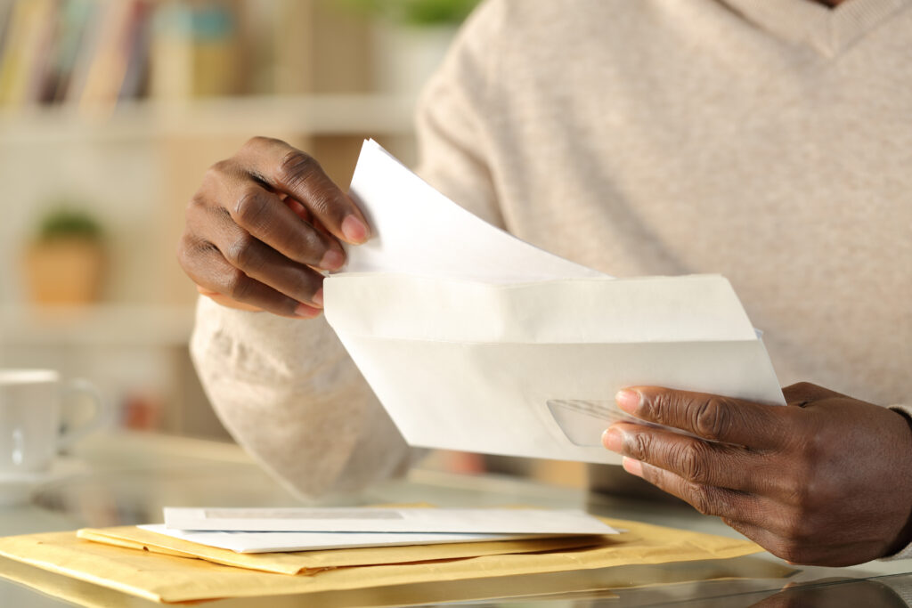 Person removing a letter from an envelope while sorting through mail at home.