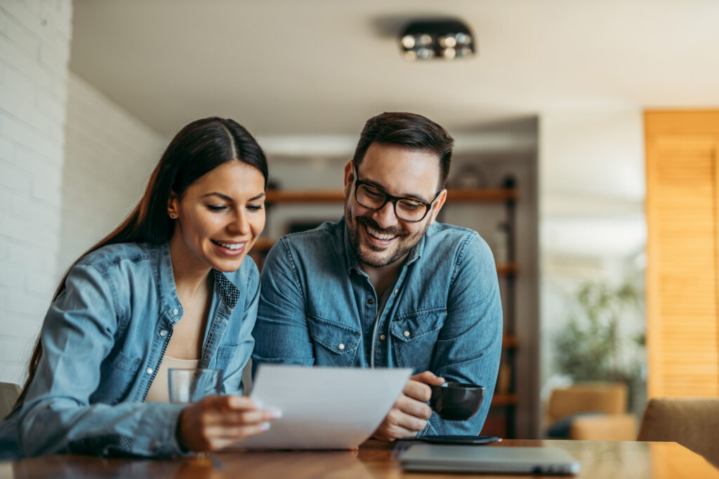 Couple smiling while reviewing paperwork together at a table at home.