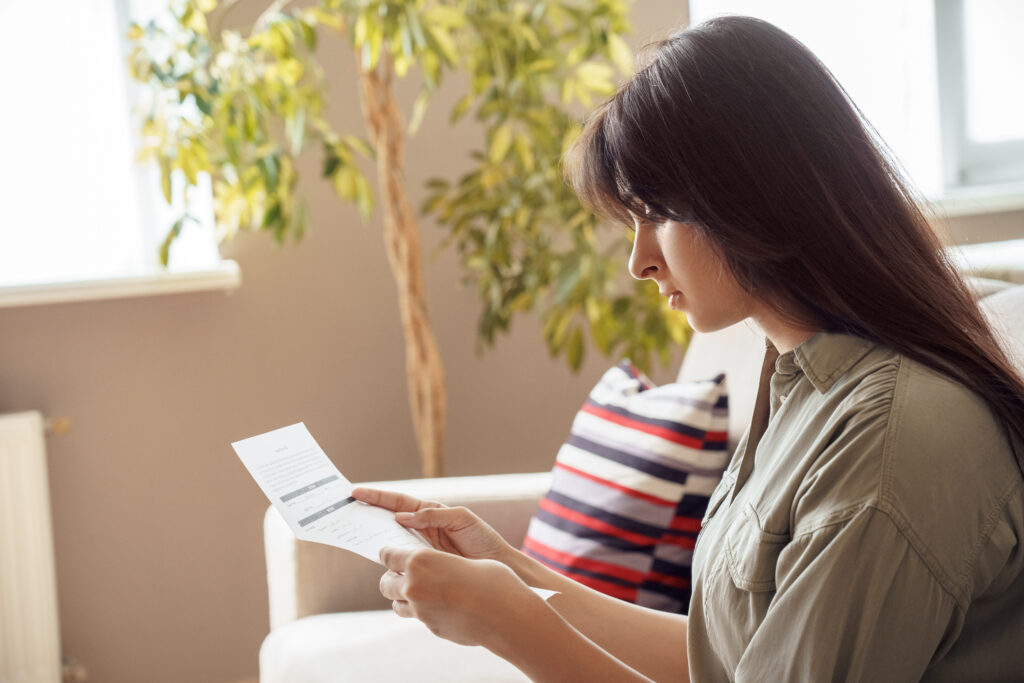 Woman sitting at home and reviewing a financial document.