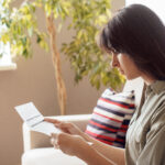 Woman sitting at home and reviewing a financial document.