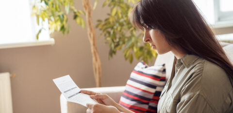 Woman sitting at home and reviewing a financial document.