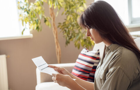 Woman sitting at home and reviewing a financial document.