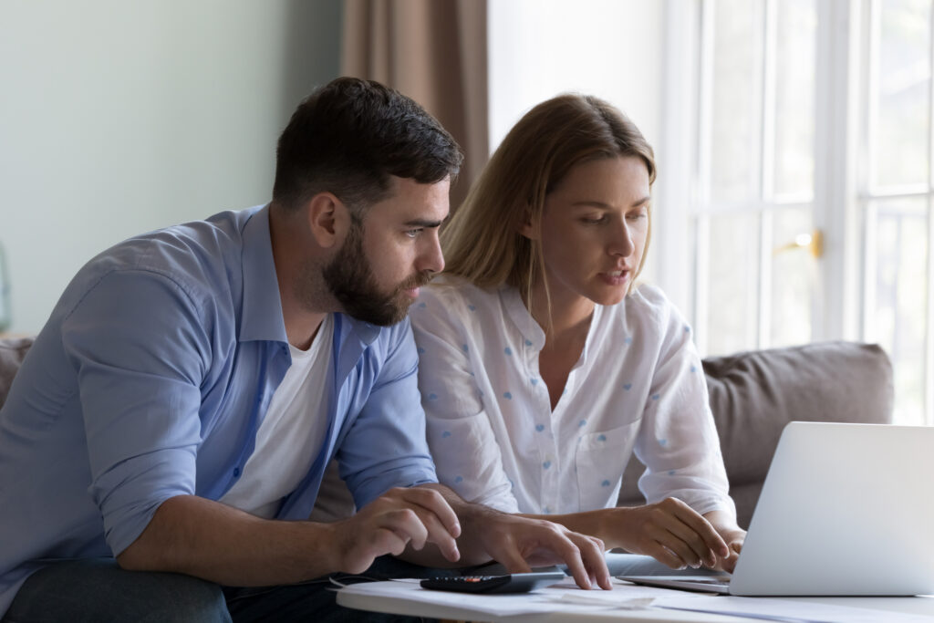 Couple reviewing their finances together on a laptop at home.