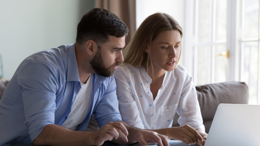 Couple reviewing their finances together on a laptop at home.