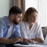 Couple reviewing their finances together on a laptop at home.