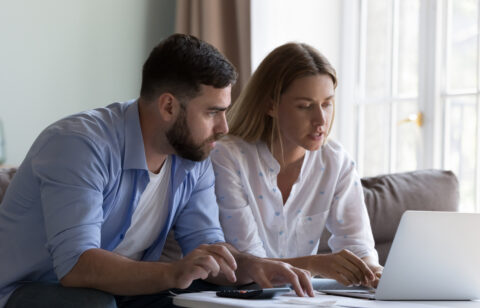 Couple reviewing their finances together on a laptop at home.